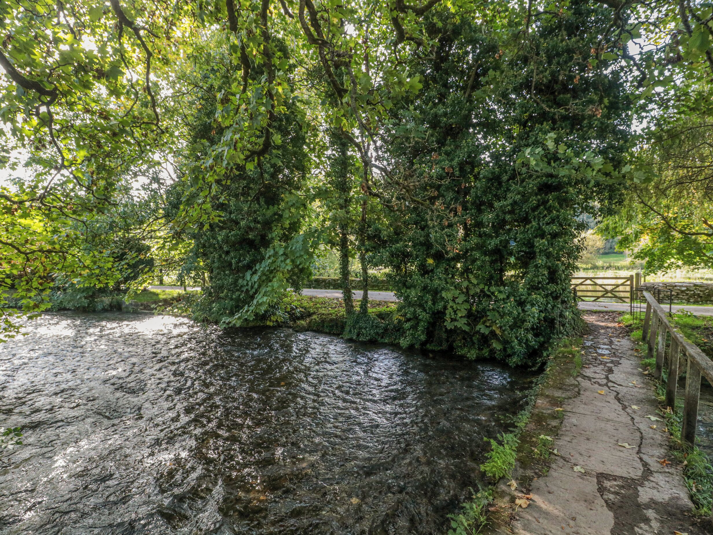A river with a stone bridge and a wooden fence.