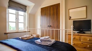 Une chambre à coucher avec un lit, une fenêtre, une armoire et un téléviseur.