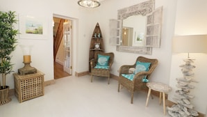 A spacious hallway with wicker furniture, a mirror, and a decorative lamp. - Waverley House (Beaumaris)