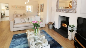 A living room with a sofa, a fireplace, a TV, and a mirror. - Waverley House (Beaumaris)