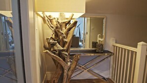 A wooden sculpture in a hallway with a mirror reflecting a staircase and a white railing. - Diddly Squat, 43 Dart Marina (Dartmouth)