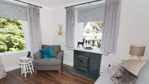 A cozy living room with a fireplace, a sofa, a chair, and a small table. - Shepherd's Crook (Ambleside)