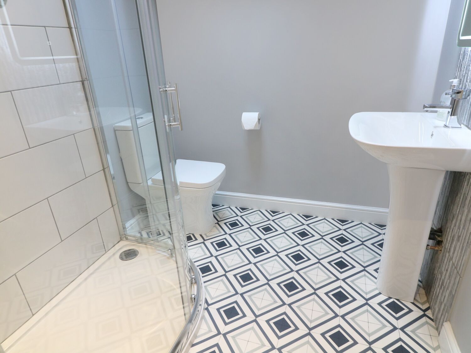 A bathroom with a glass shower enclosure, a toilet, and a sink.
