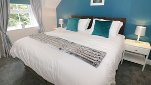 A bedroom with a large bed, two bedside tables, a window with curtains, and a framed picture on the wall. - Shepherd's Crook (Ambleside)