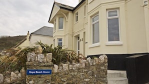Un bâtiment à deux étages, doté d’un mur en pierre et d’une enseigne bleue sur laquelle on peut lire : « Hope Beach House ».