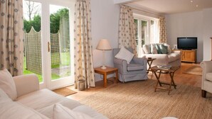 A spacious living room with a sofa, armchairs, a TV, and a large window with curtains. - Homefield House (Kingsbridge)