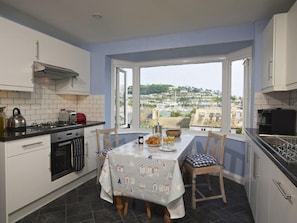 A kitchen with a dining table set for breakfast, overlooking a scenic view.