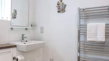A bathroom with a white sink, a mirror, a towel rack with a folded towel, and a small decorative item on the wall.