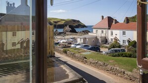 A coastal view with a road, parked cars, and buildings. - 4 Armada House (Kingsbridge)