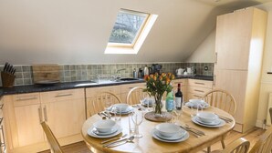 A dining area with a round wooden table set for four, surrounded by wooden chairs. A skylight above the table provides natural light. - 4 Armada House (Kingsbridge)