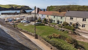 A coastal village with traditional houses, a marina, and a rocky shoreline. - 4 Armada House (Kingsbridge)