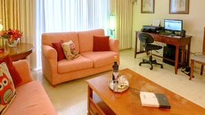 A living room with a sofa, coffee table, and a desk with a computer. - Beating Heart City Family Home Next to Beach (Chania)