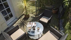 A patio with wicker furniture, a glass table, and a potted plant. - 16 Courtenay Street (Salcombe)