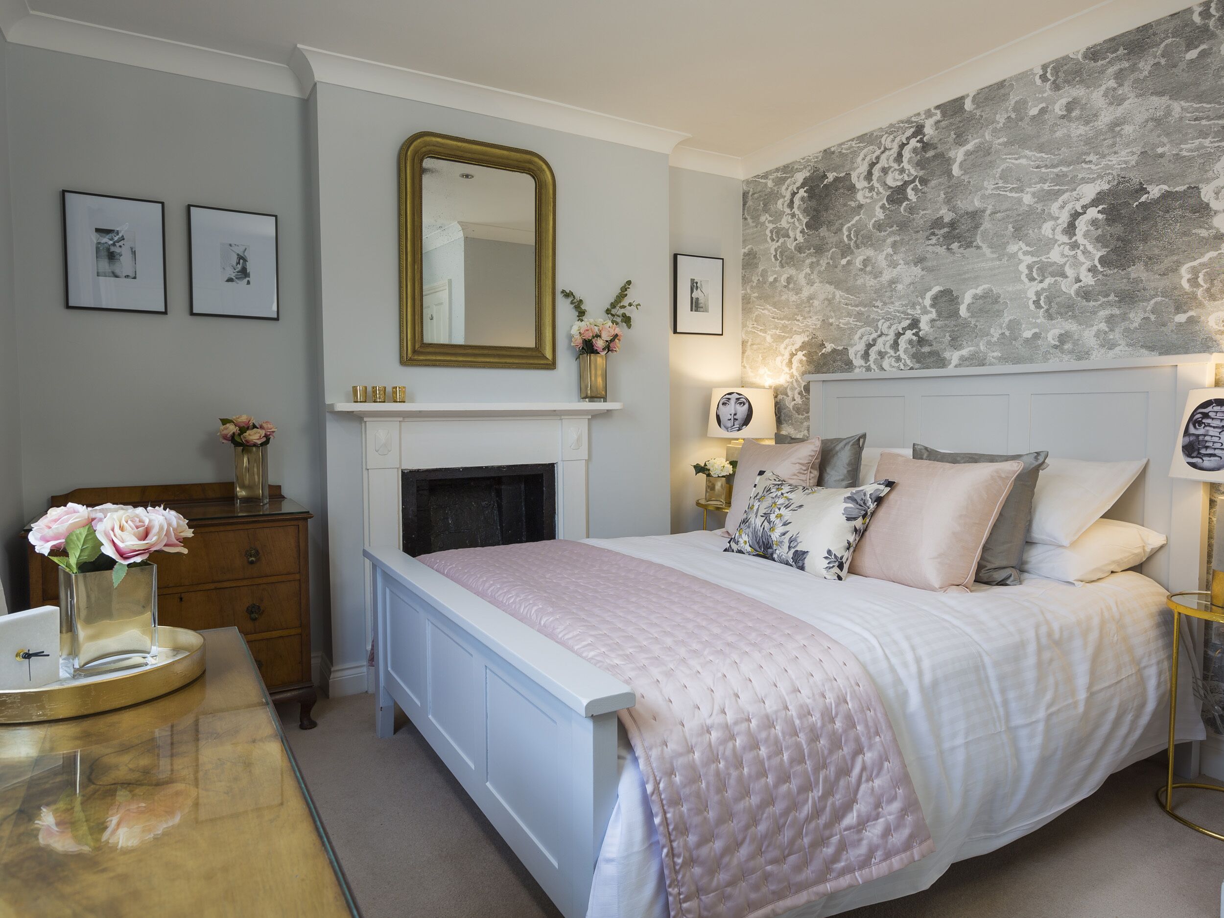 Un dormitorio con cama, cómoda, espejo, chimenea y pared de piedra.
