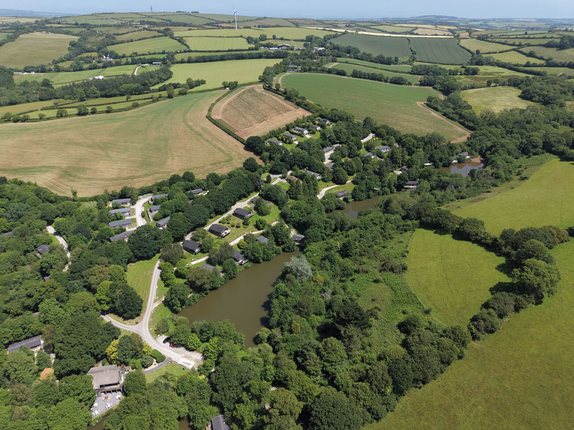 An aerial view of a rural area with fields, a river, and scattered houses.