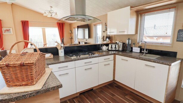 Een kleine keuken met witte kastjes, een gasfornuis en een spoelbak.