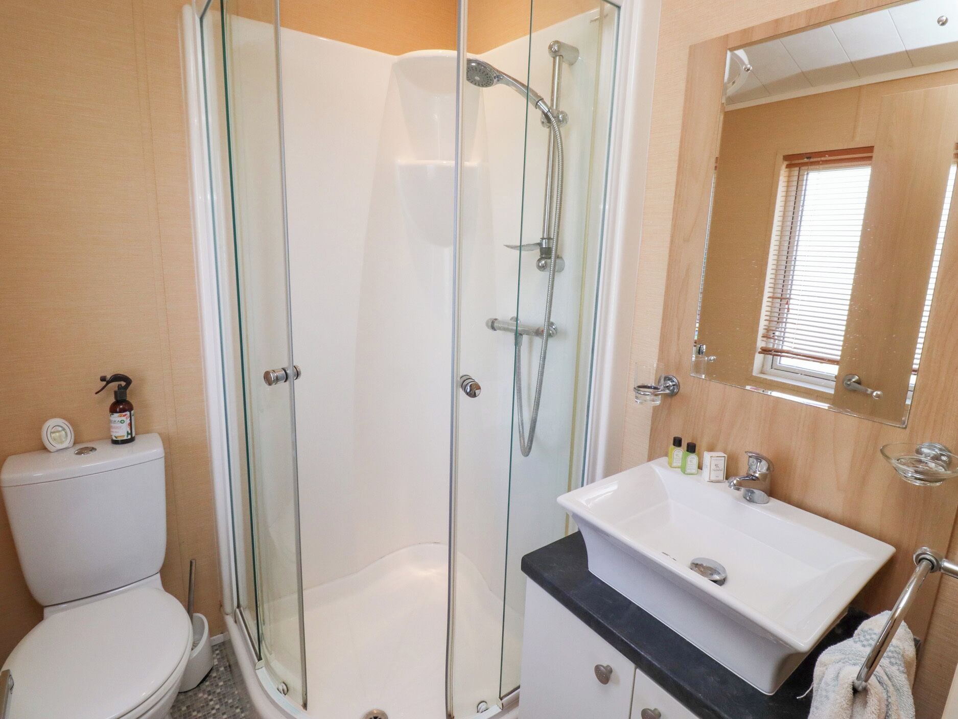 A bathroom with a glass-enclosed shower, a white sink, and a toilet.
