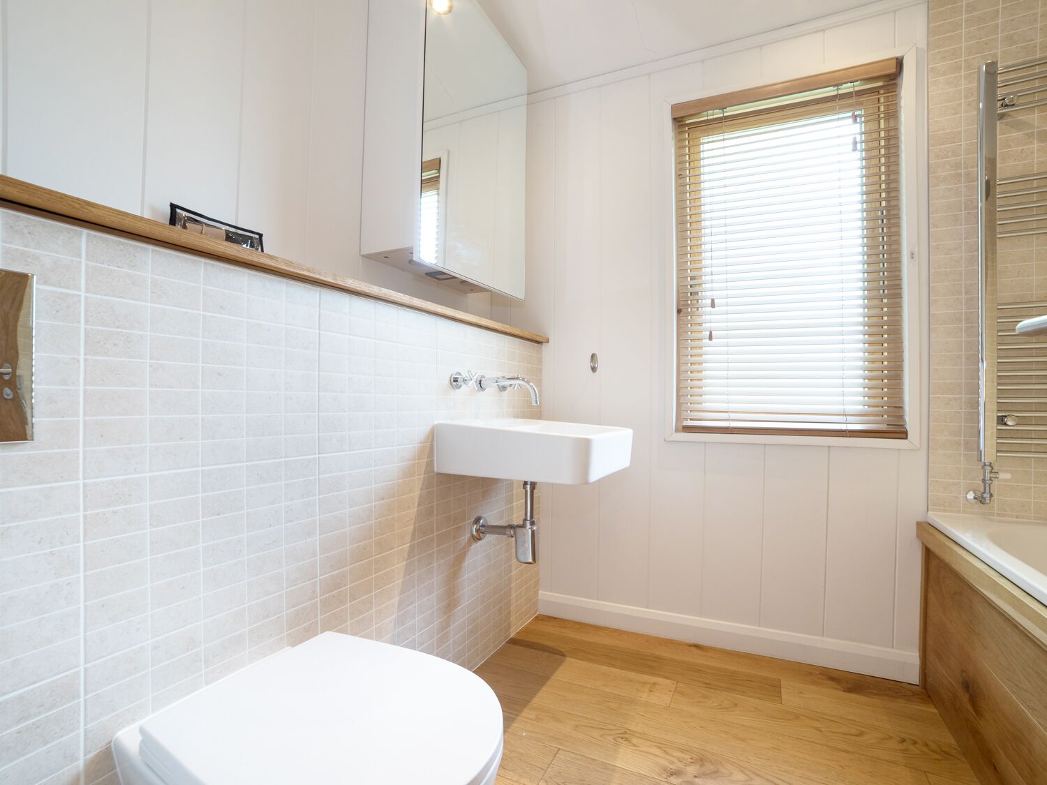 Un bagno con un water bianco, un lavandino e una finestra con persiane.