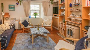 Un salon confortable avec un canapé, deux fauteuils, une table basse et une bibliothèque.