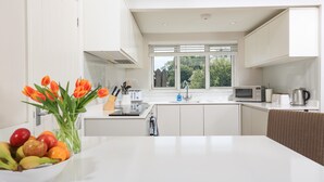 A modern kitchen with white cabinets, a microwave, a kettle, and a fruit bowl on the counter. - Keepers Lodge, Hillfield Village (Dartmouth)