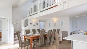 A spacious dining area with a high ceiling, a staircase leading to an upper level, and a view of the adjacent living area. - Keepers Lodge, Hillfield Village (Dartmouth)