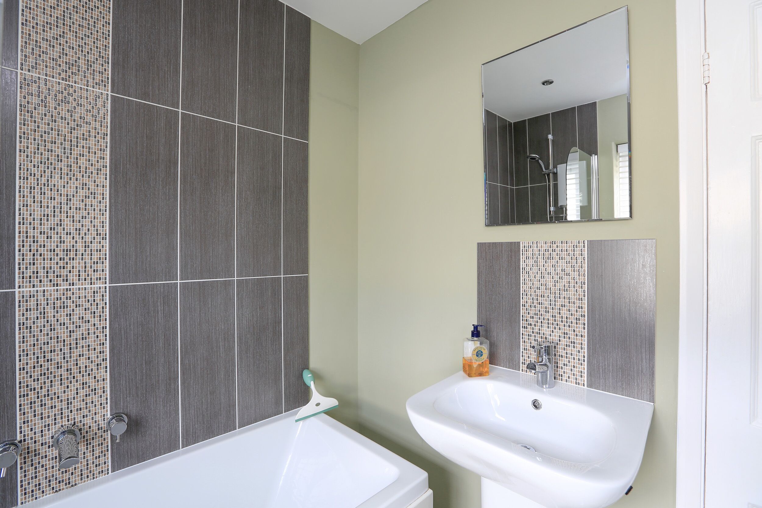 A bathroom with a bathtub, a sink, and a mirror.