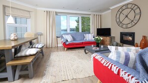 Una sala de estar moderna con un ventanal grande, un sofá rojo, una mesa de comedor de madera y un gran reloj de pared.
