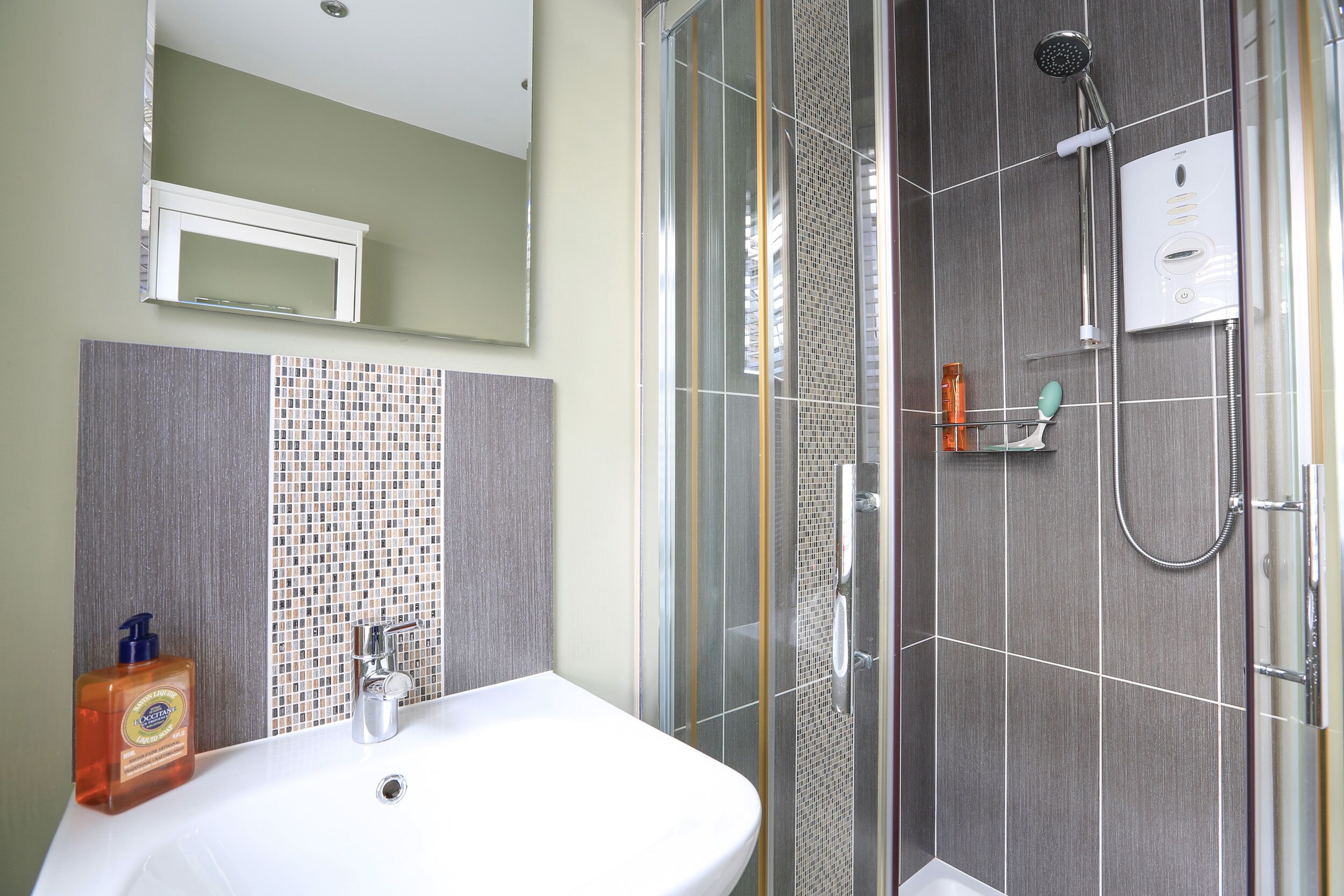 A bathroom with a white sink, a shower with a handheld showerhead, and a glass-enclosed shower stall.