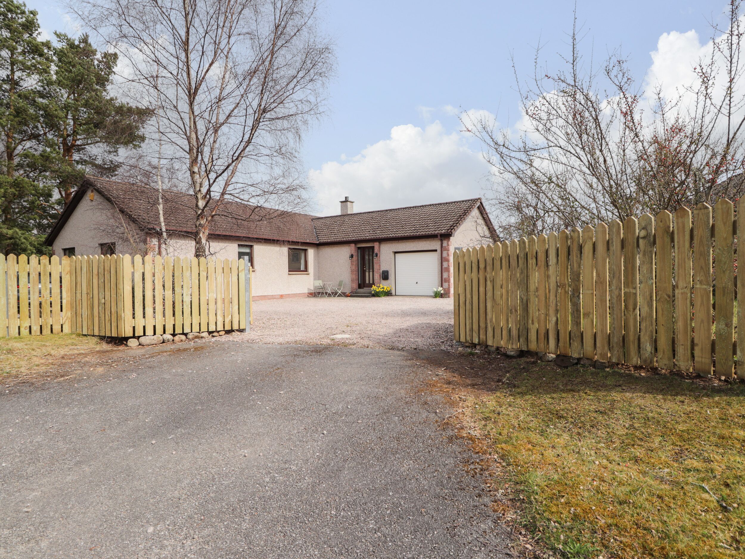 Une maison à deux étages avec une allée en gravier menant à un garage.