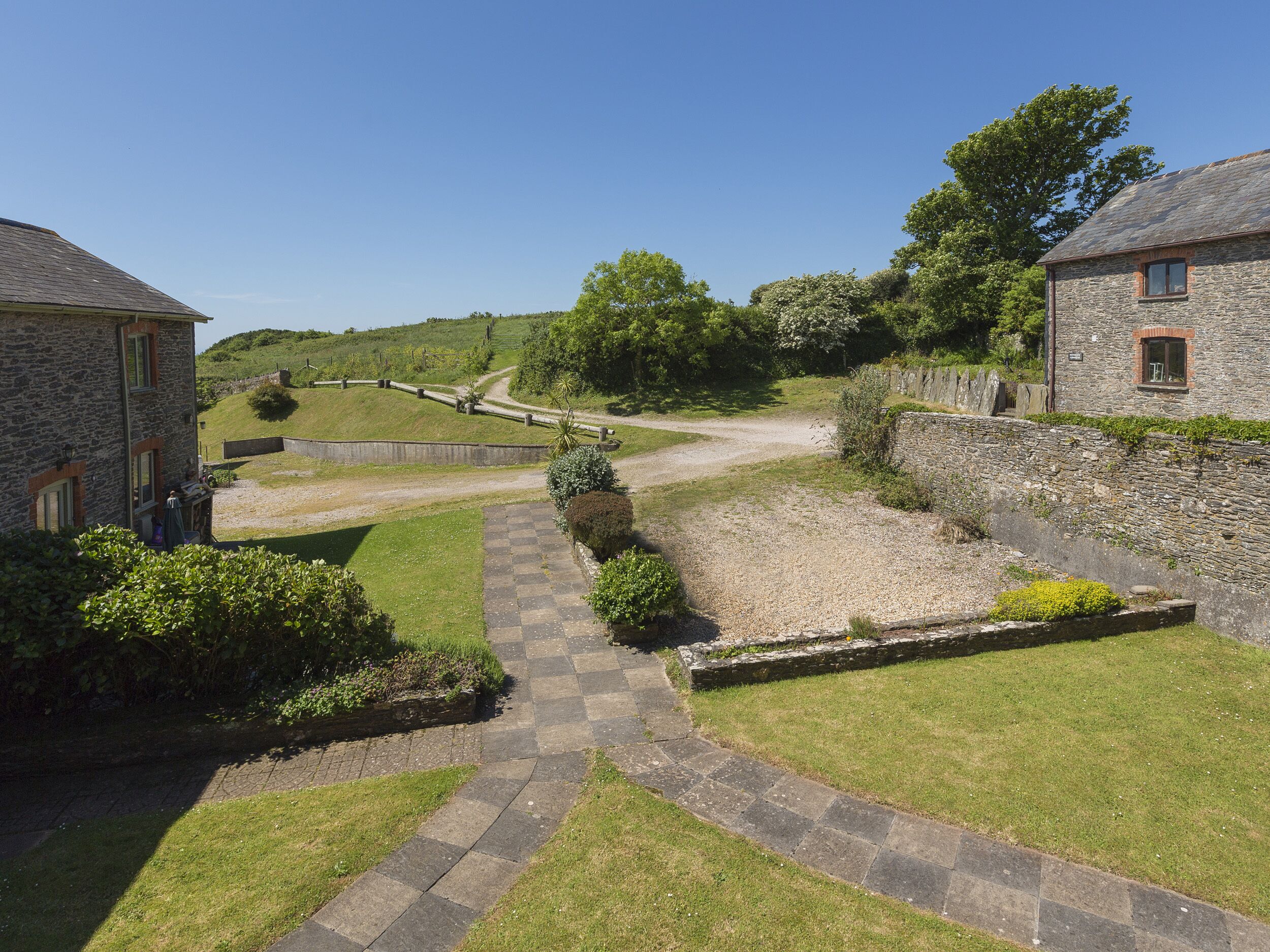 En stenlagd gång leder fram till en byggnad av sten, vars fasad har ett rutmönster.