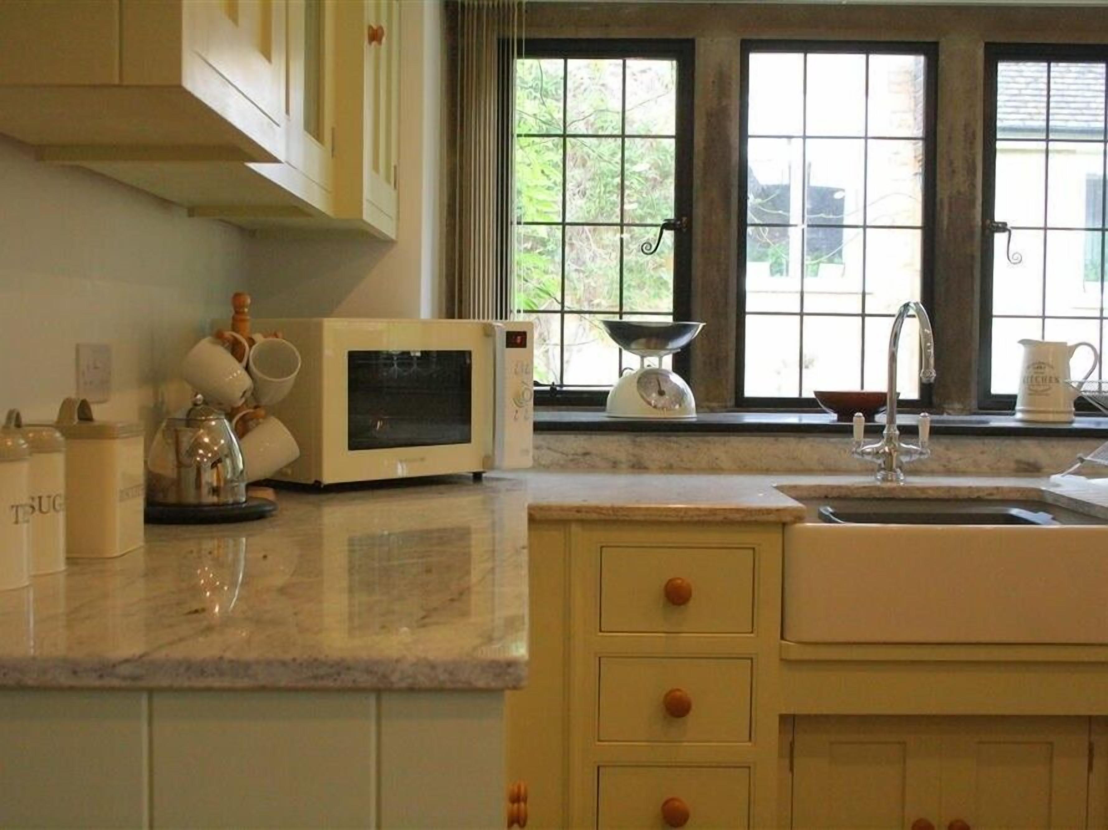 Una cocina con microondas, hervidor y lavabo.