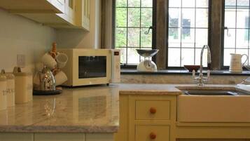 Una cocina con microondas, hervidor y lavabo.
