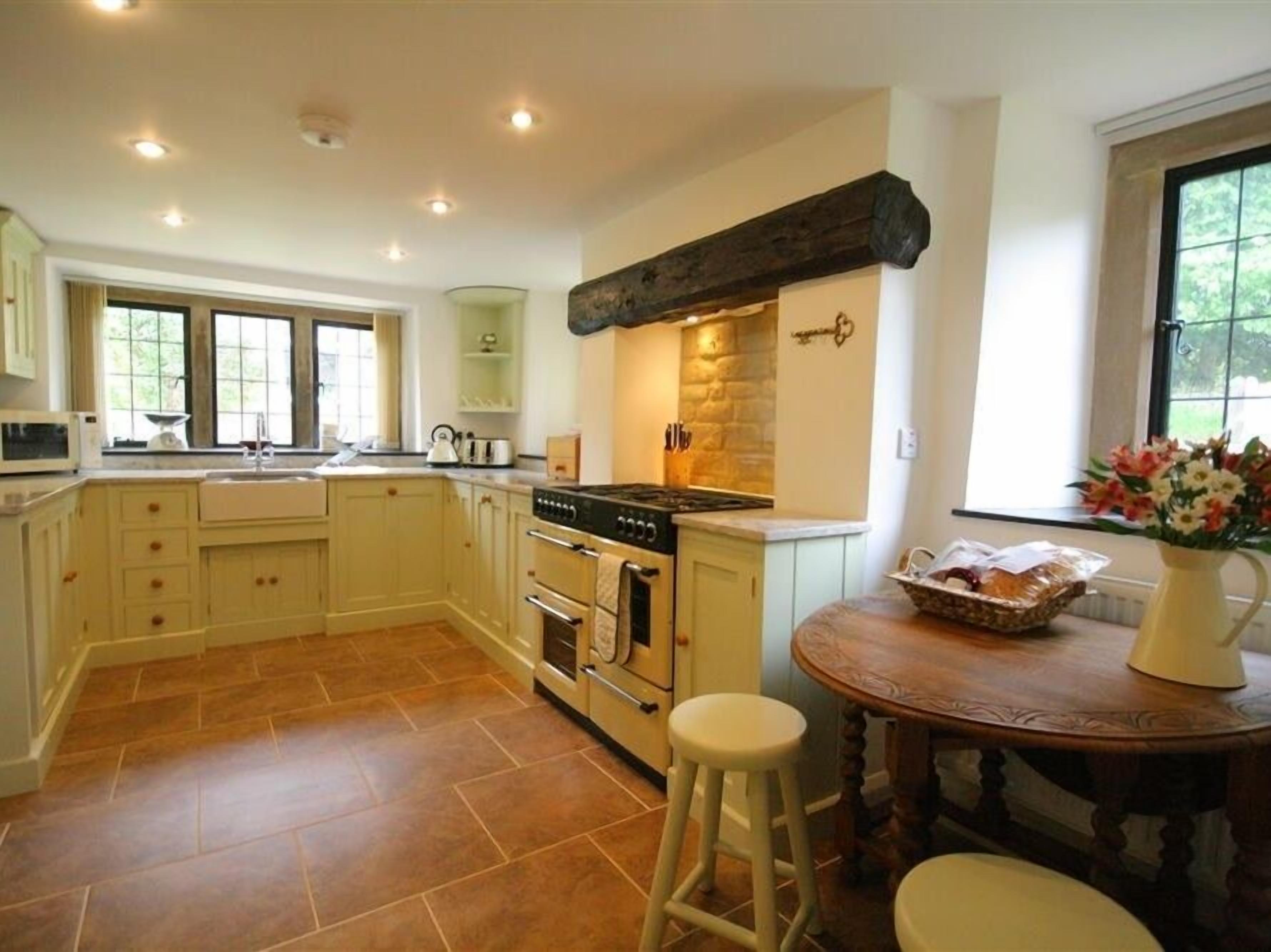 A kitchen with a large island, a stove, and a sink. There is a window with a view of greenery outside.