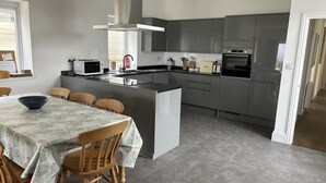 Une cuisine moderne avec des meubles de couleur grise, un îlot central et un coin repas comprenant une table et des chaises.