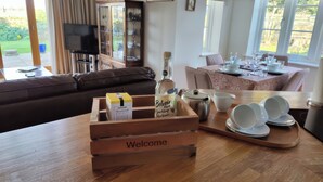 A cozy living room with a wooden coffee table, a sofa, and a dining area with a table set for two.