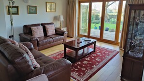 A living room with a brown leather sofa, a wooden coffee table, and a red patterned rug.