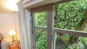 A room with a large sliding glass door leading to a lush green garden. - Holemire Barn (Cockermouth)