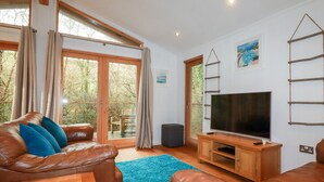 Una sala de estar con un sofá de cuero marrón, un tapete azul, un mueble de televisión de madera y un televisor grande.