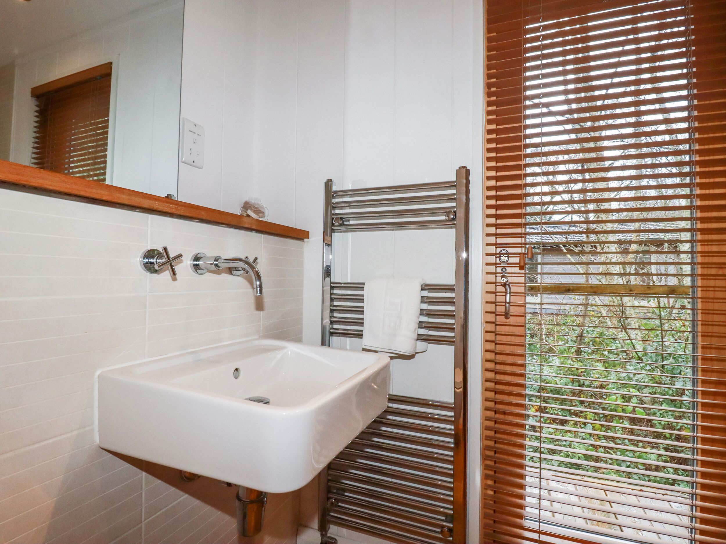 A bathroom with a white sink, chrome faucet, and towel rack.