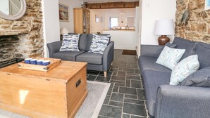 Een woonkamer met een grijze bank, een houten salontafel en een stenen muur.