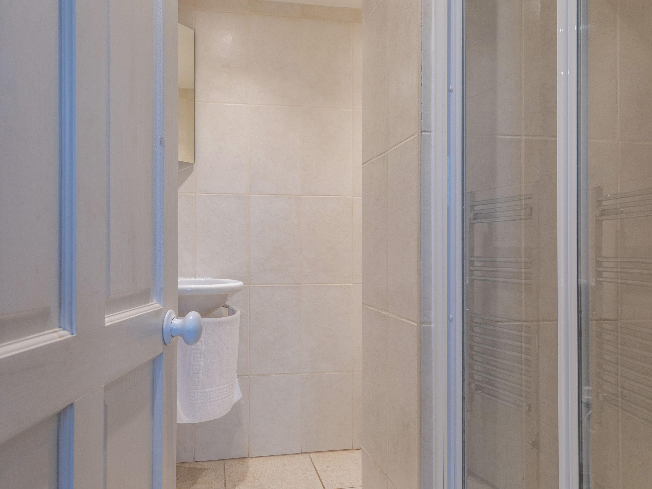 A bathroom with a toilet, a towel hanging on the wall, and a glass shower enclosure.