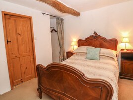 Un dormitorio con una cama de madera, dos mesitas de noche con lámparas, un armario de madera y una puerta.