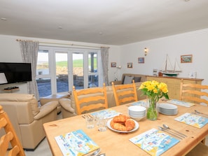 Enjoy meals with family and friends at this spacious dining area, featuring a large table and comfortable seating.