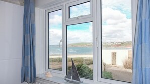 Une chambre avec vue sur la mer, donnant sur un balcon où est posé un modèle de voilier.