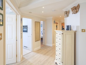 Stylish hallway leads to a cozy bedroom, featuring a door to another room and a cabinet with a shelf and storage.
