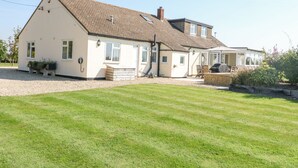 Une maison à deux étages, dotée d’un toit en pente, d’un porche à l’avant et d’un espace extérieur couvert aménagé en salon.