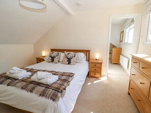 A bedroom with a bed, two bedside tables, a wooden dresser, and a radiator. - The Clealings (Witney)