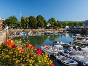 Enjoy a serene waterfront setting with boats docked along the lush greenery-lined harbor.