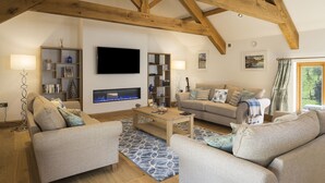 A cozy living room with a fireplace, sofas, a coffee table, and bookshelves. - Butterwell Barn (Dartmouth)