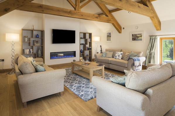 A cozy living room with a fireplace, sofas, a coffee table, and bookshelves.